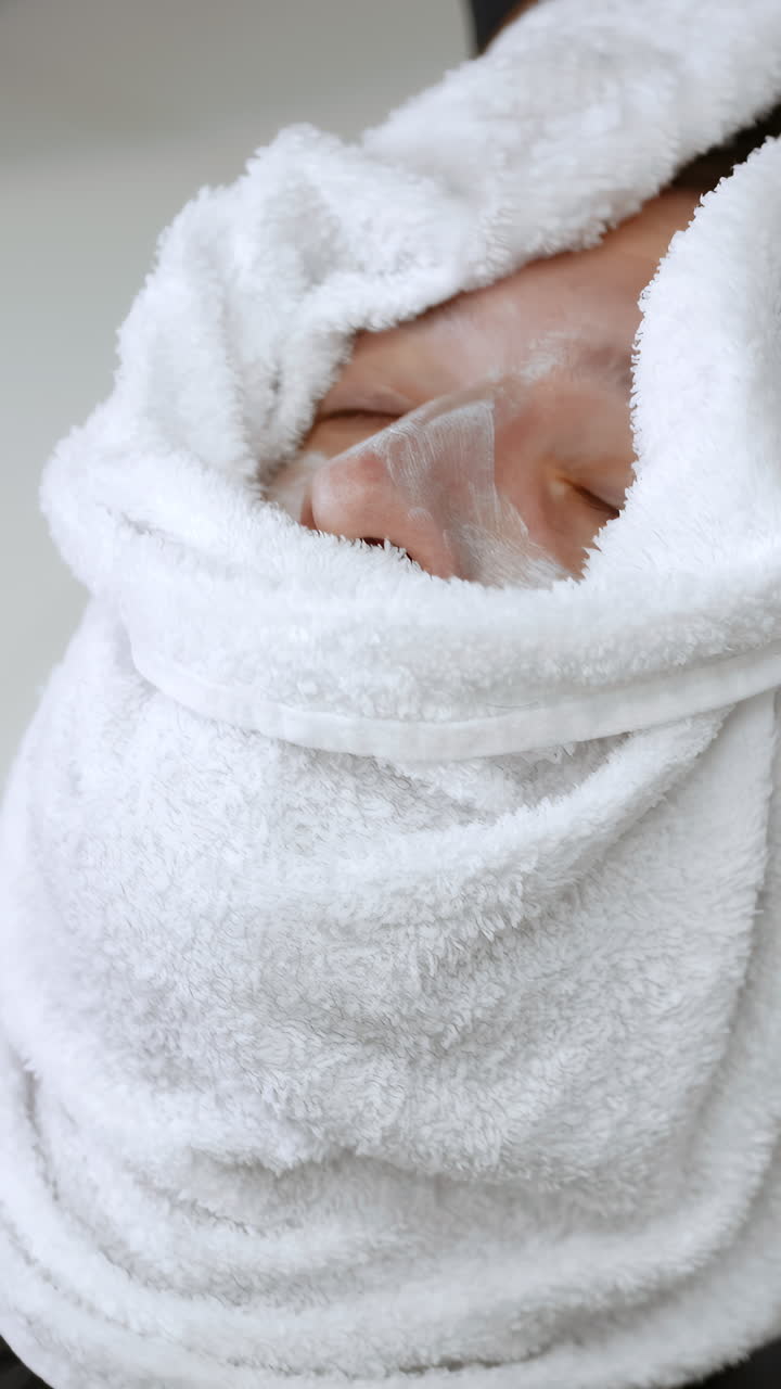 Woman receiving a facial treatment with a towel wrapped around her head