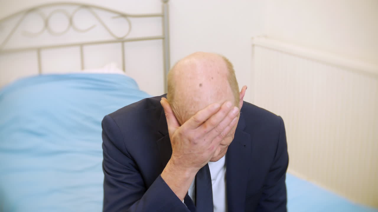 우울하고 생각에 잠긴 채 침대에 앉아 정신 건강에 어려움을 겪고 있는 피곤한 고위 사업가