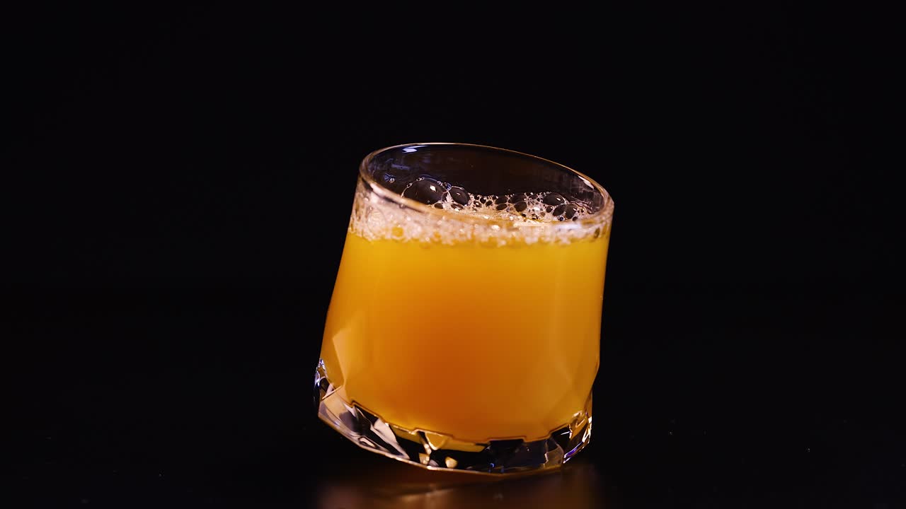 Bicchiere di succo d'arancia che ruota su sfondo nero