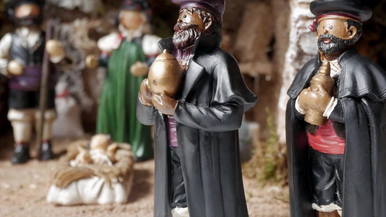 Filmagem em close-up começa com foco em um dos presentes dos Reis Magos, em seguida, afasta-se para revelar toda a cena do presépio, mostrando o Menino Jesus, animais e detalhes intrincados.