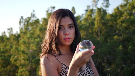 una hermosa mujer hispana encantadora en un mundo de fantasía mística con una bola de cristal mágica y una mirada sensual