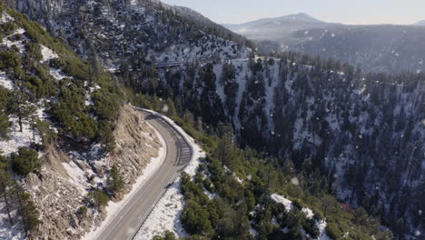 aerial shot of winding mountain road in snowing winter landscape