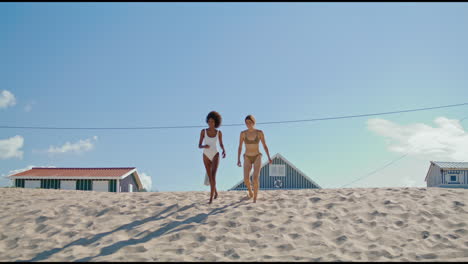 pareja lgbt corriendo en la playa en bikini, chicas felices pasando el verano en la orilla del océano.