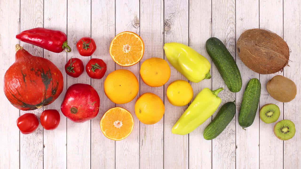 Red, yellow, orange and green fruits and vegetables appear on wooden theme. Stop motion