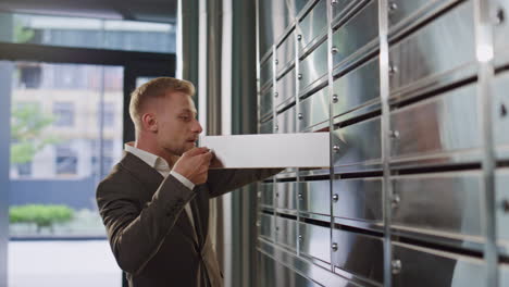 man open private mailbox checking correspondence closeup. upset guy look letter