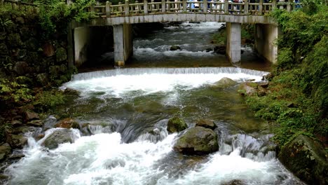 el arroyo de la montaña que desciende más allá de las rocas de musgo - bajo el puente coreano