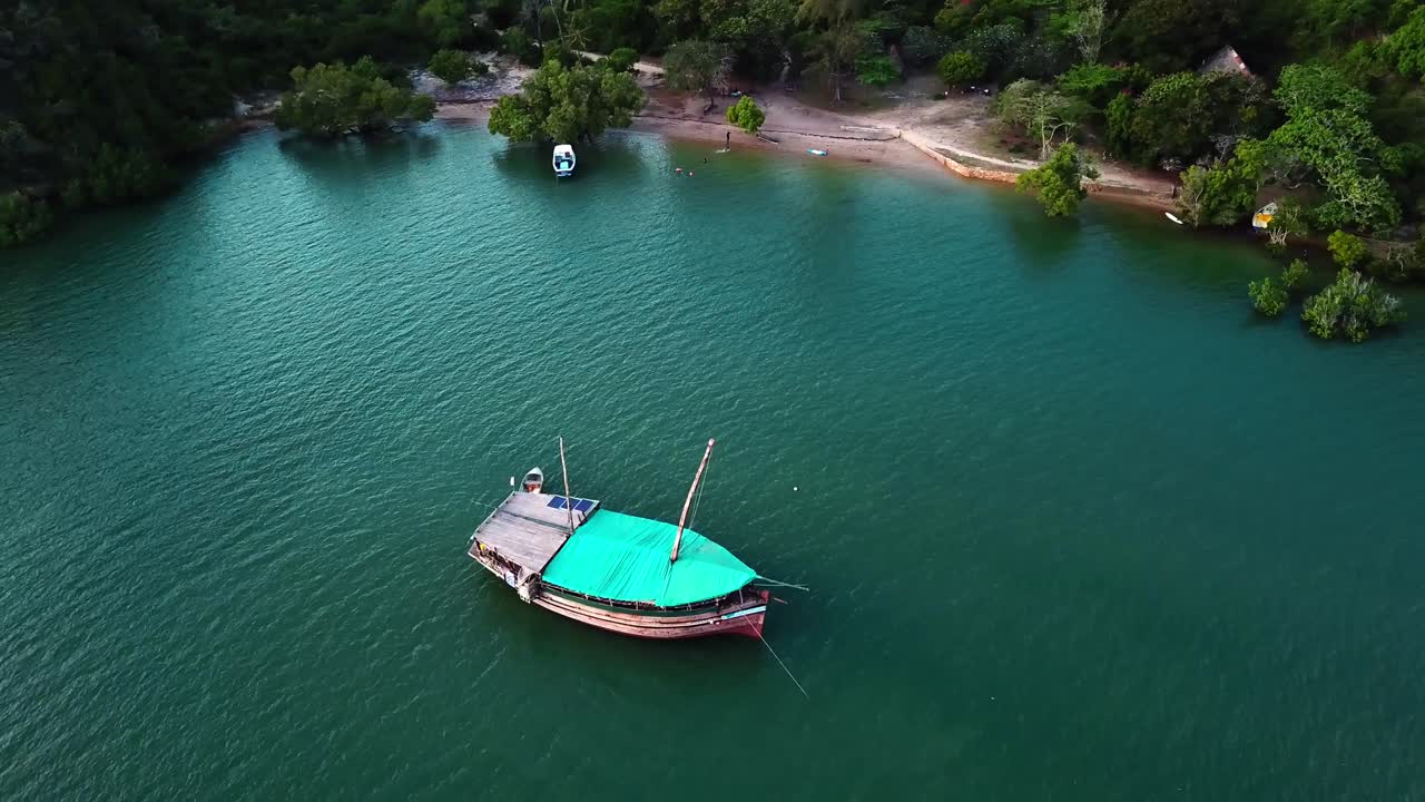 un barco dhow de madera flotando en las tranquilas aguas turquesas de kilifi creek, kenia, áfrica oriental