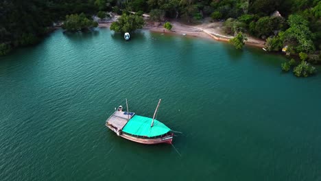 Un-Barco-Dhow-De-Madera-Flotando-En-Las-Tranquilas-Aguas-Turquesas-De-Kilifi-Creek,-Kenia,-áfrica-Oriental