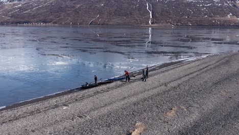 kayak adventure group landing on volcanic beach in iceland fjord, aerial