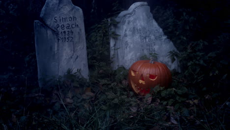 Calabaza-De-Halloween-En-Llamas-Y-Lápida-En-El-Cementerio,-Luz-De-Luna-Intermitente-Y-Niebla,-Plano-Medio-Del-Control-Deslizante