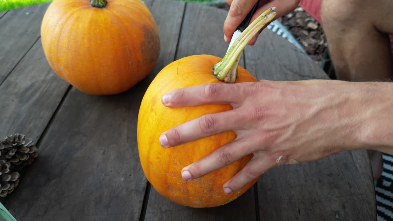 잭 오 랜턴을 만들기 위해 호박을 열고 있는 남성 손의 클로즈업