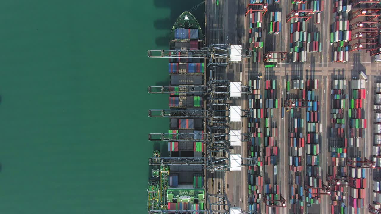 Large Container Ship docked at Hong Kong commercial port, top down aerial view including Stacks of Shipping containers on a holding platform