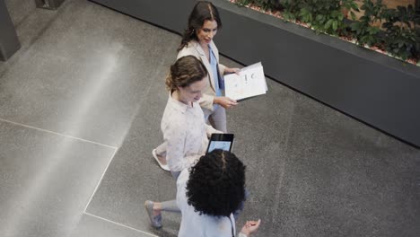 Diverse-female-colleagues-in-discussion-using-tablet-in-office-foyer,-slow-motion