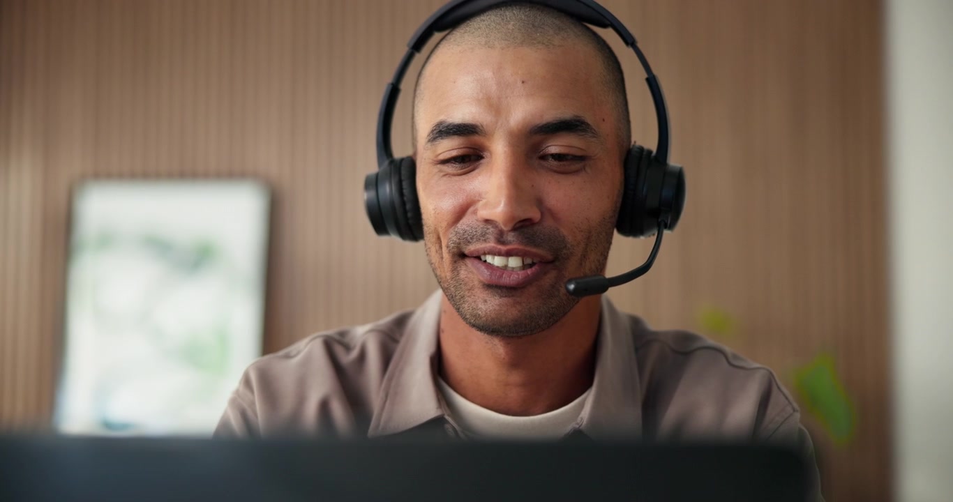 Smiling Man Wearing Headset Having a Video Call on Laptop