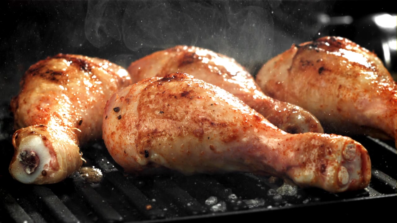 Deliziose cosce di pollo che cuociono su una griglia fumante
