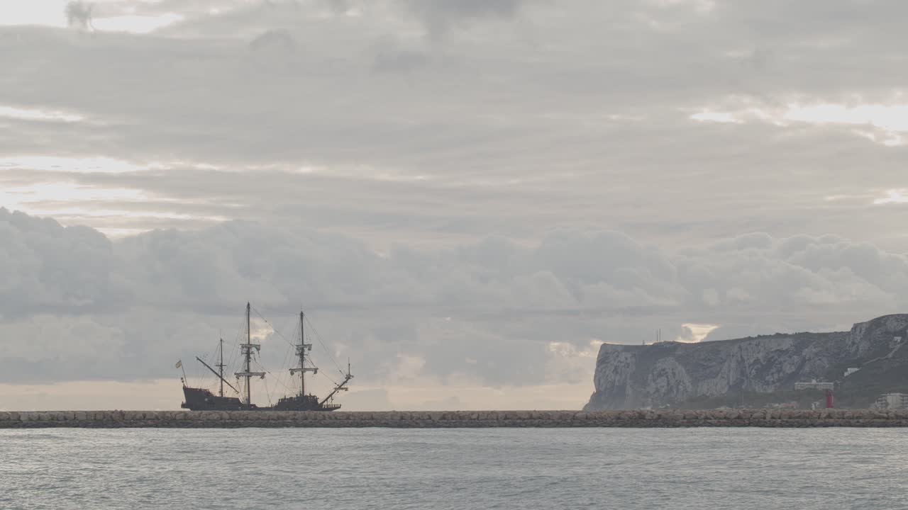 galeón del siglo xvi réplica de andalucia barco que llega al puerto en un hermoso día nublado al amanecer detrás de un rompeolas con la montaña al fondo