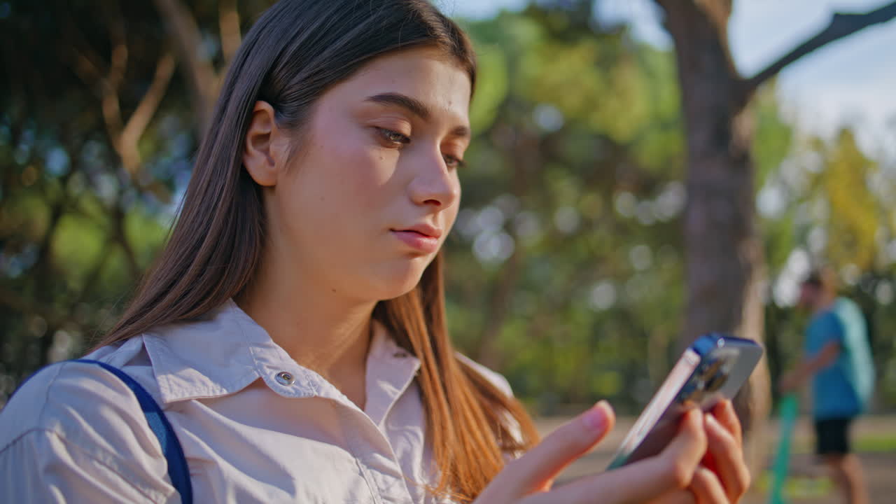 mujer preocupada enviando mensajes por teléfono móvil en el parque soleado de primer plano. señora insatisfecha