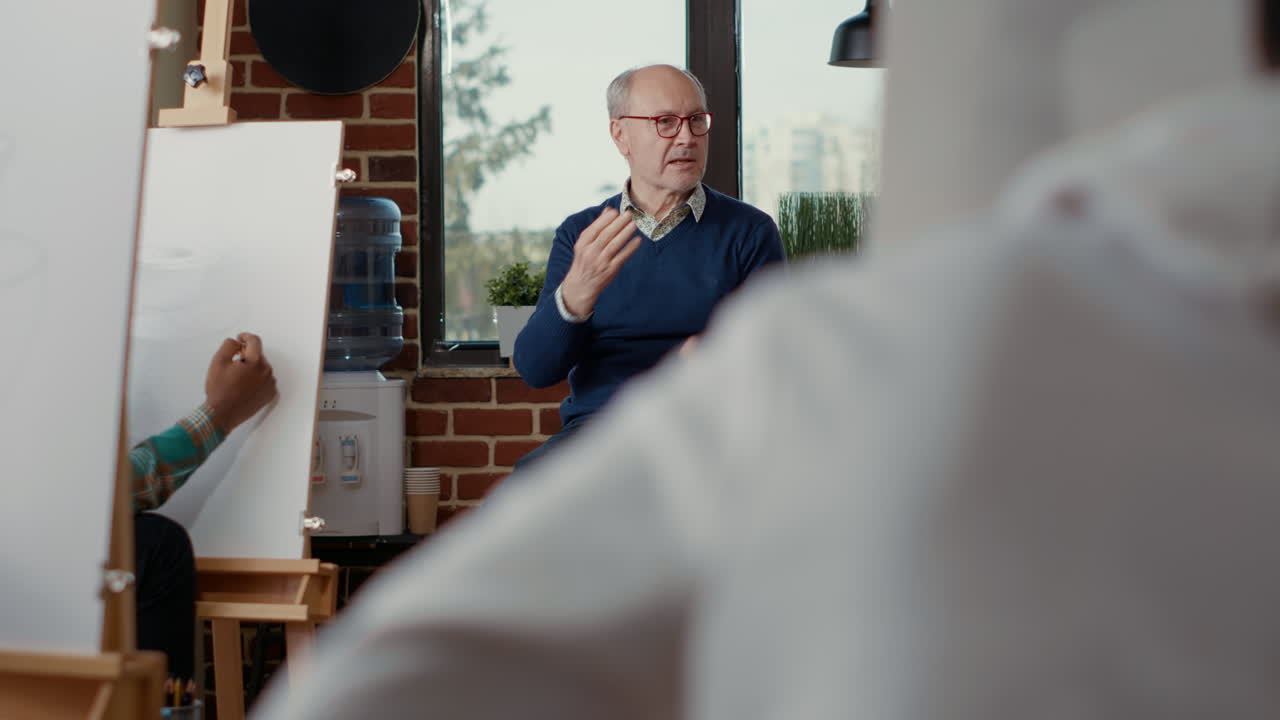 Senior man teaching art students to draw artwork on canvas