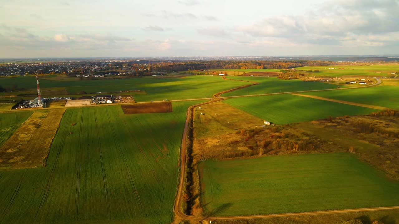 дрон снимает машины, движущиеся по узкой дороге, проходящей через зеленые поля в солнечный осенний день, бельгия