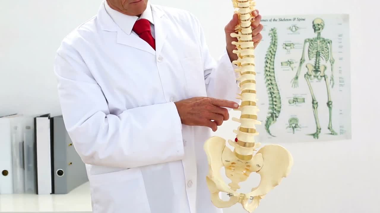 médico explicando el modelo de esqueleto a la cámara