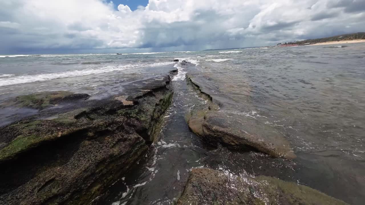 hermoso paisaje en cámara lenta de pequeñas olas que se estrellan sobre grandes rocas de la playa de tibau do sul cerca de pipa, brasil en río grande do norte durante un día nublado de verano