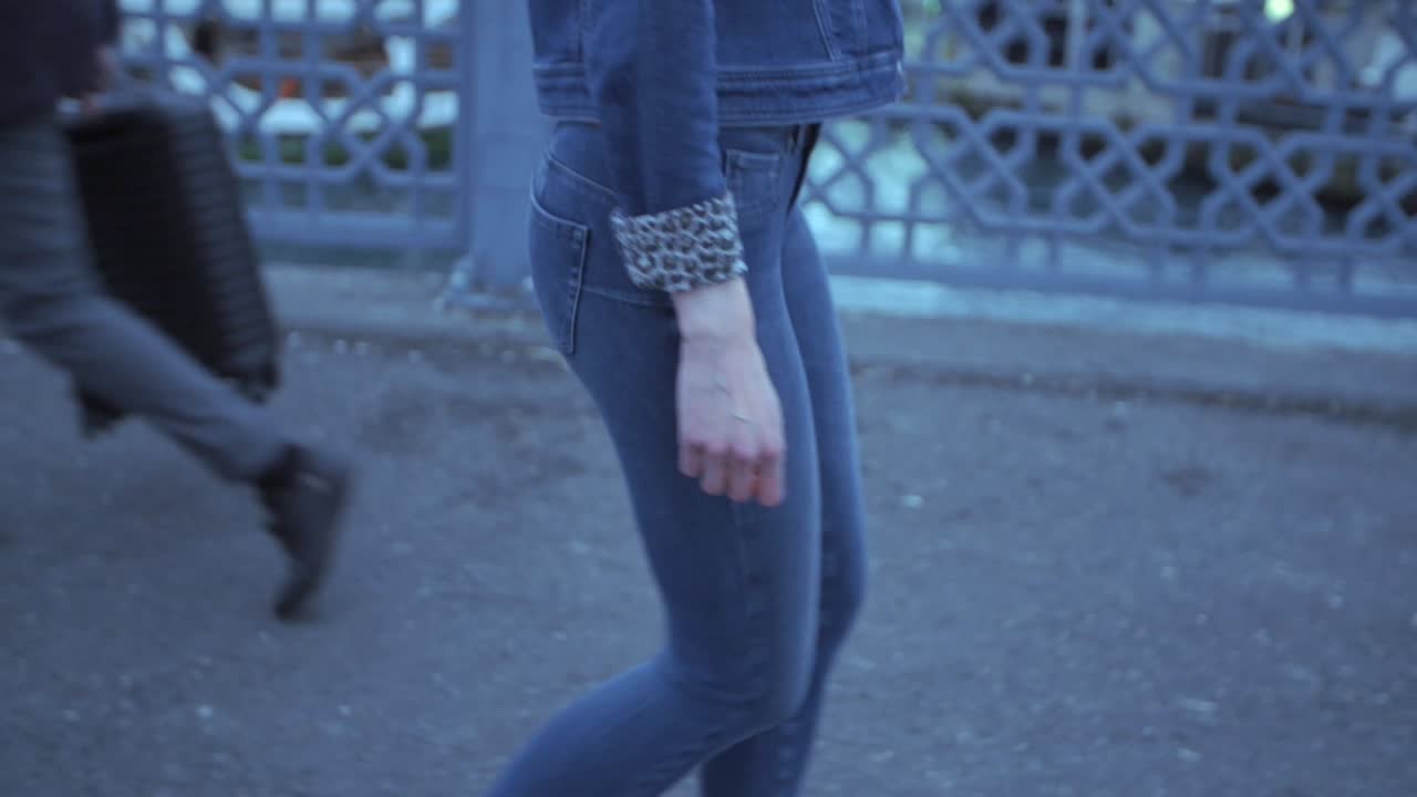 donna che cammina per strada, indossa blue jeans e giacca di jeans con maniche leopardate
