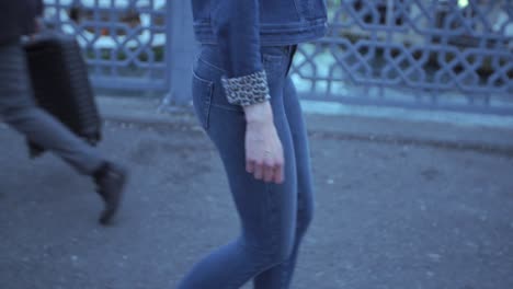 Woman-walking-down-the-street,-wearing-blue-jeans-and-denim-jacket-with-leopard-print-sleeves