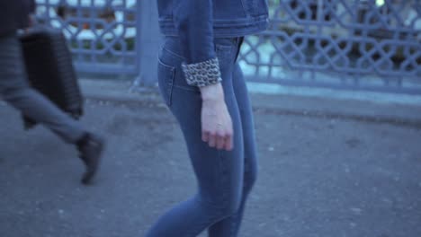 woman walking down the street, wearing blue jeans and denim jacket with leopard print sleeves