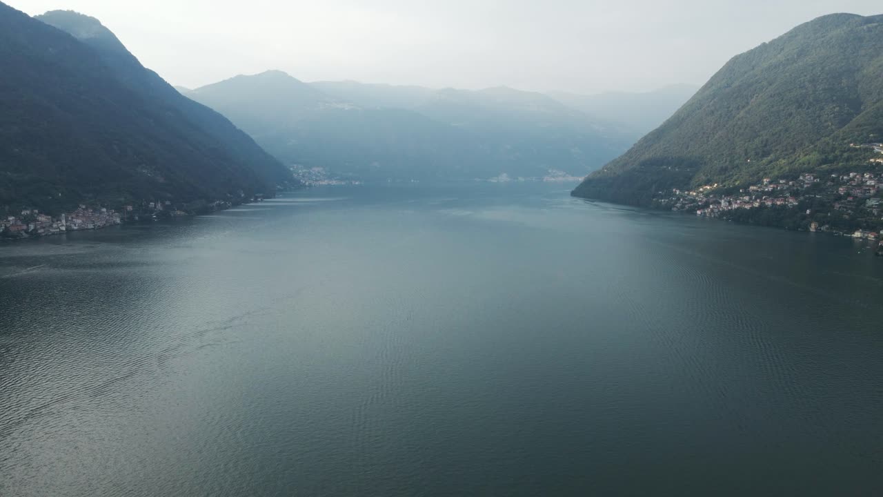 이탈리아의 코모 호수 위에서 넓은 산악 풍경을 보여주는 기울어지는 드론