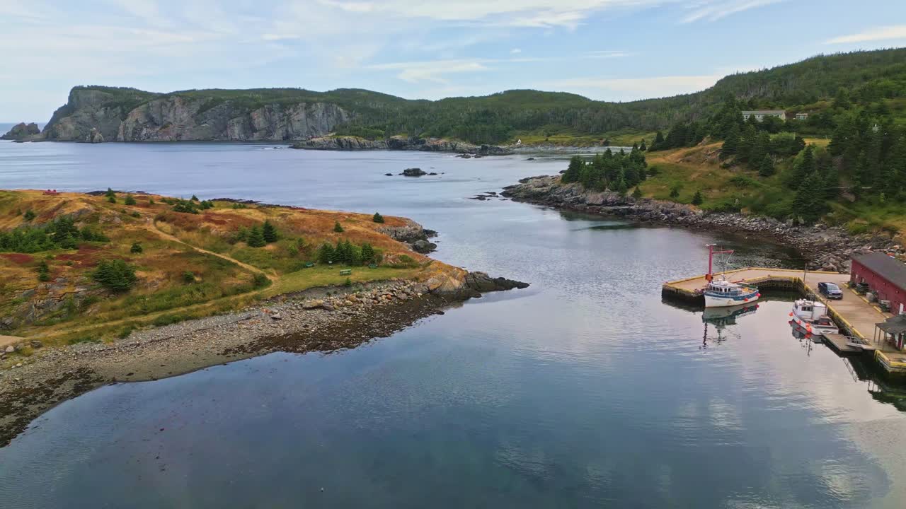 Drooni liitää Brigus Southin tyynen lahden yllä ja kuvaa ruohoista niemeä ja kivikkoista rantaviivaa, jossa tyynet vedet ja kaukaiset kalliot kohtaavat Newfoundlandin rosoisella rannikolla.