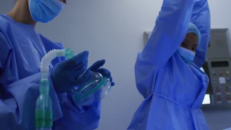 cirujano con ropa protectora sedando a un paciente caucásico con gas durante una operación en el hospital