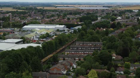 Static-aerial-view-over-the-town-of-Royston-in-England,-UK-with-a-freight-train-passing-through