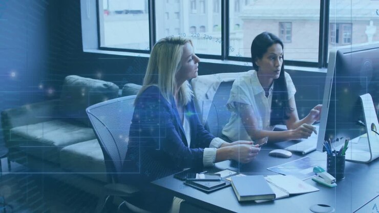 Animation of data processing and light trails against two diverse women discussing at office