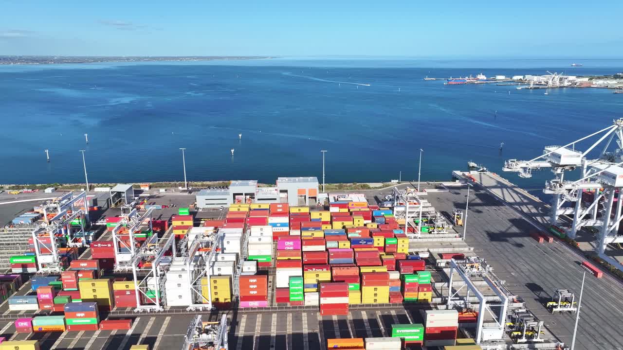Container yard beside blue coastal waters at Melbourne shipping terminal viewed from above