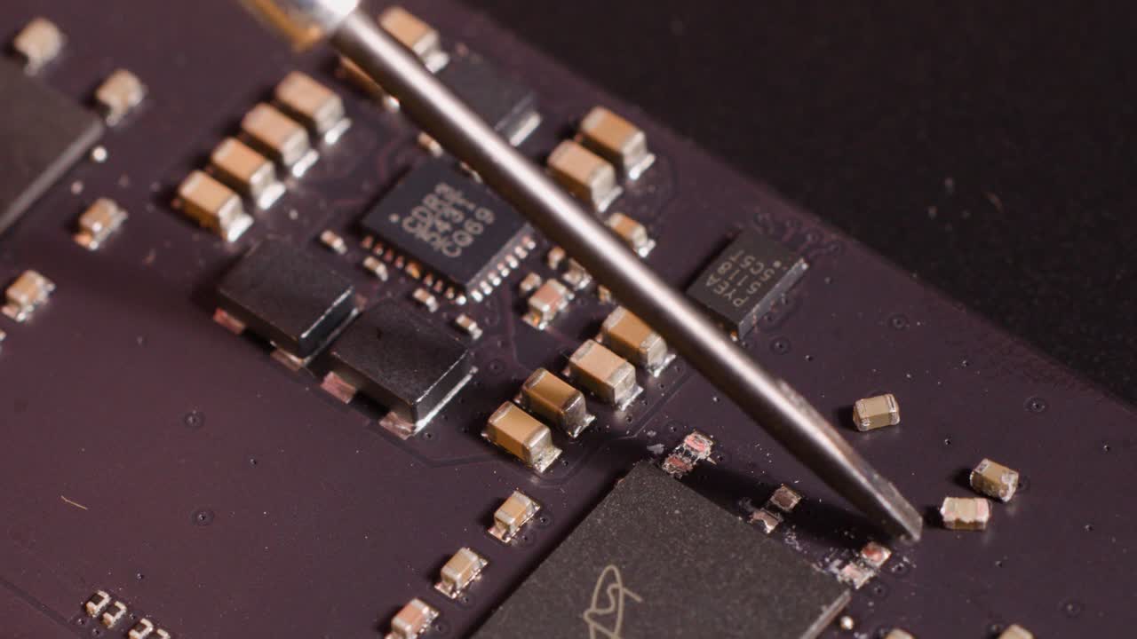 Extreme close-up of a metal probe carefully adjusting microchips and capacitors on a motherboard