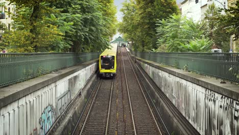 yellow underground train in daylight of berlin and on rails driving into tunnel