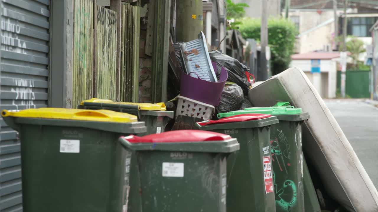 contenedores de ruedas, basura doméstica y un viejo colchón usado en una calle residencial en el centro de sydney, australia