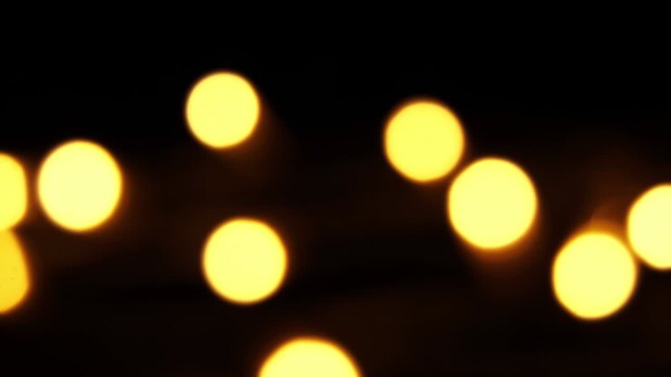Abstract bokeh background in motion. shining, blurred golden particles, lights. bright bokeh from garlands on dark background. New year or Christmas festive backdrop