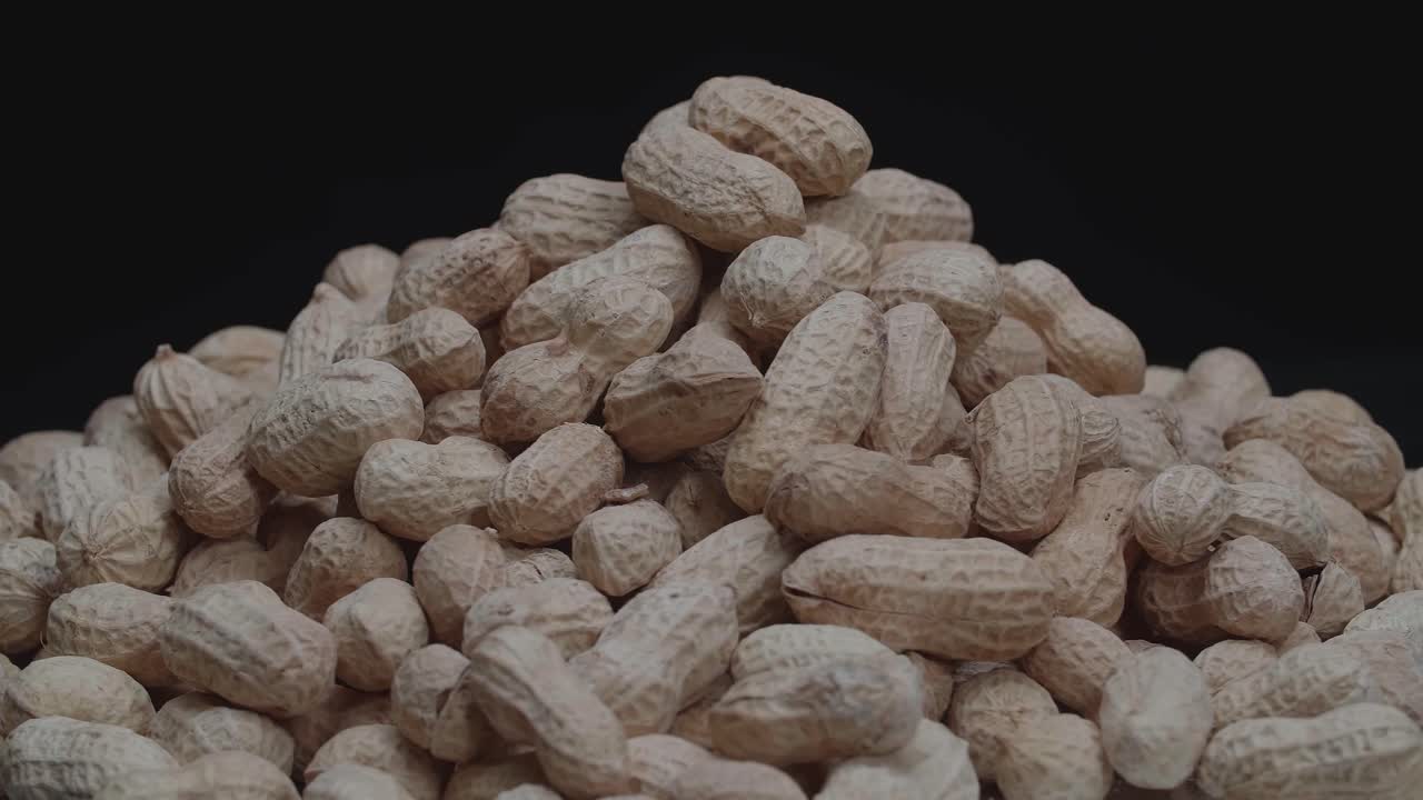 Rotation Of Peanuts Are Unpeeled. They'Re An Excellent Plant-Based Source Of Protein In The Black Background