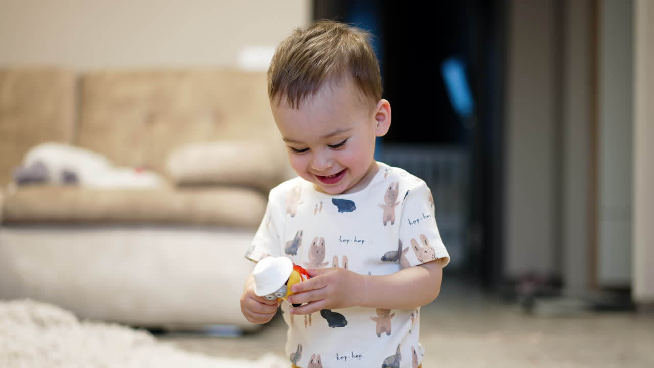 Bellissimo bambino sorridente che tiene in mano un giocattolo. Il bambino gioca con un giocattolo esultando gioiosamente. Sfondo sfocato.