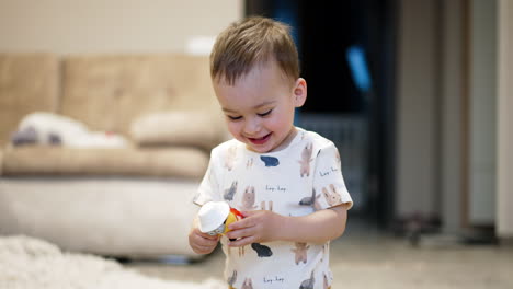 beautiful smiling baby holding a toy. kid plays with a toy cheering joyfully. blurred backdrop.