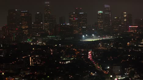 Los-Angeles,-California-city-skyline-at-nighttime---pullback-aerial-reveal