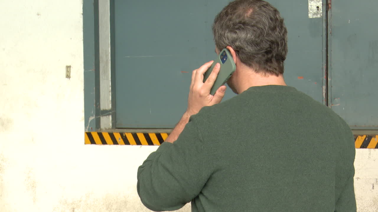 Man talking on phone outside a warehouse
