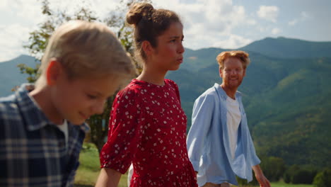 Family-summer-vacation-mountains.-People-walking-green-slope-communicating.