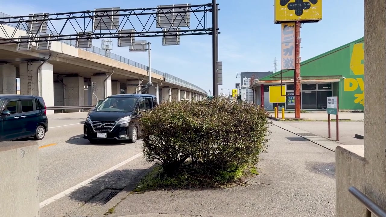 Uma câmera portátil sobe escadas de concreto com uma rampa para bicicletas em direção a uma rua ensolarada.