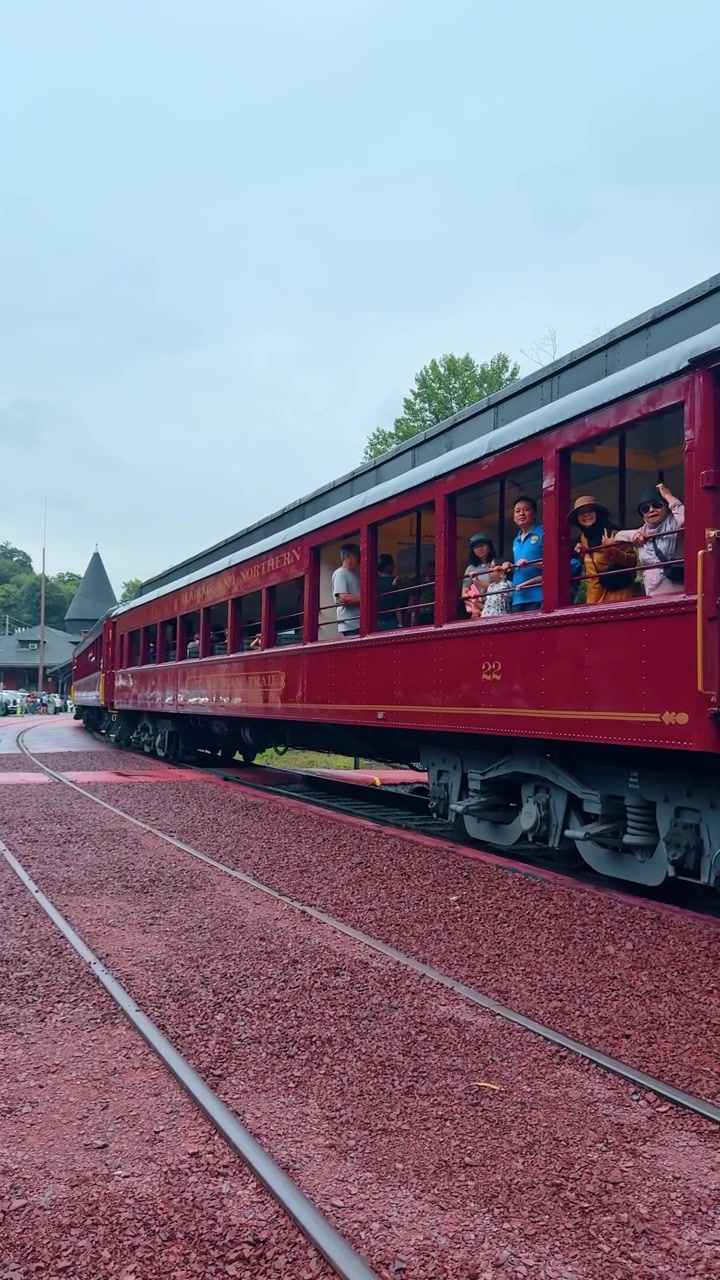 Jim Thorpe, AS, 2 Juli 2025: Tampilan samping gerbong kereta penumpang merah di rel. Profil eksterior gerbong penumpang bergaya kayu merah antik dengan orang-orang melihat keluar jendela selama perjalanan.