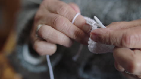 close up of elderly woman hands knitting needles