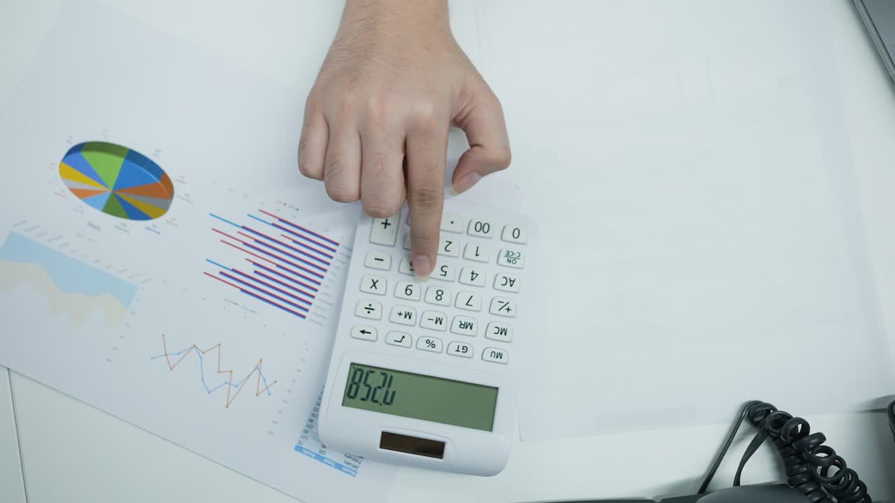 escena de cámara lenta vista superior del hombre contable usando el cálculo en la calculadora para resumir o considerar en el informe estadístico en la oficina para el concepto de negocios y financieros