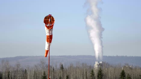 Windsack-Am-Flughafen-Quesnel-Mit-Wogendem-Dampf-Aus-Industrieschornsteinen-In-British-Columbia,-Kanada