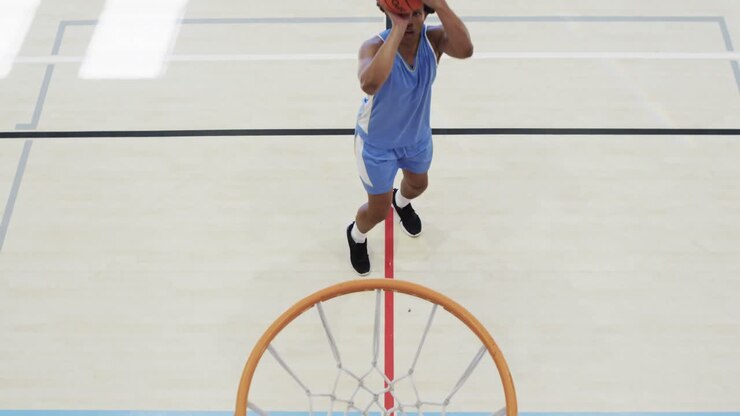 High angle of african american male basketball player shooting ball at hoop on court, slow motion
